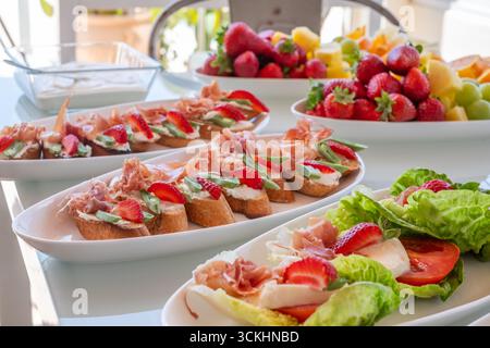 Spuntini leggeri splendidamente disposti su piatti, con frutta vibrante e condimenti salati, ideali per la condivisione in incontri informali e serate Foto Stock