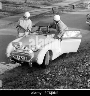 Austin-Healey Sprite MK1 Frogeye: Icona del Rally Spirit degli anni '1960. In questa vibrante immagine del 1960 del Nordic Women's Rally, due partecipanti femminili si trovano accanto alla Austin-Healey Sprite MK1 "Frogeye", un'auto sportiva britannica compatta celebrata per i suoi fari sgargianti e simili a rane e per il rivoluzionario design monoscocca. Lanciata nel 1958 da Donald Healey Motor Company sotto la guida di BMC, la Sprite offriva un divertimento accessibile con un motore da 948 cc serie A da 43 cv, trazione posteriore e un telaio leggero da 1.500 lb, ideale per una guida vivace e per gli sport motoristici. Il suo significato risiede nella democratizzazione dello sport CA Foto Stock