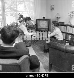 Televisione negli anni '1950 Un design tv tipico dell'era, con la possibilità di visualizzare solo trasmissioni in bianco e nero e un solo canale. Le manopole sui comandi anteriori consentono di controllare l'immagine e l'audio. Le trasmissioni televisive in Svezia sono iniziate ufficialmente il 15 settembre 1956, lanciate da Radiotjänst con il programma Sigge slår på stora trumman. È il personaggio televisivo Pekka Langer con la sua famiglia a casa nel 1957. Sullo schermo, è visibile il modello di test classico. Durante gli anni '1950, la televisione era un mezzo nuovo e in rapida evoluzione. I set erano ingombranti, spesso alloggiati in armadi di legno, e presentavano un piccolo stativo Foto Stock