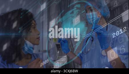 Due operatori sanitari in scrub blu che analizzano globo olografico e sovrapposizione di dati nel corridoio della clinica Foto Stock