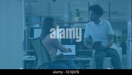 Collaborando con colleghi che indossano abiti casual alla scrivania in ufficio, con notebook, tablet e monitor Foto Stock