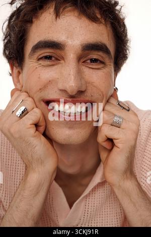 Un uomo elegante mostra il suo senso della moda, sorridendo calorosamente con fiducia e fascino. Foto Stock