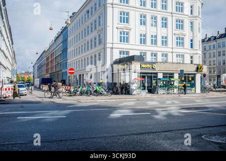 Supermercato netto nel centro di Copenhagen di giorno in primavera con parcheggio per biciclette e persone nelle vicinanze Foto Stock