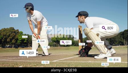 Tenendo in mano la mazza indossando il casco, il battitore e il guardiano accovacciati ai ceppi sul campo, mostrando icone grafiche Foto Stock