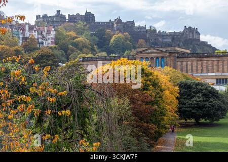 Vista del castello di Edimburgo e della Scottish National Gallery in autunno con alberi dai colori vivaci dell'autunno in primo piano Foto Stock