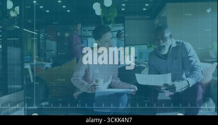 Due colleghi seduti che esaminano i documenti stampati sul divano nella sala dell'ufficio, tenendo in mano una tazza di caffè Foto Stock