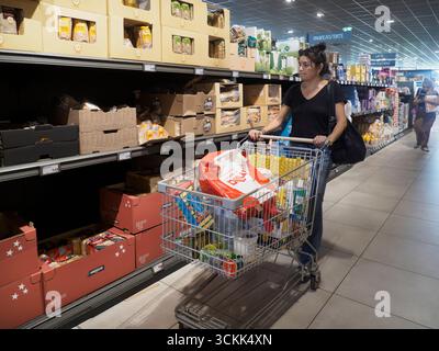 Cremona, Italia - 11 settembre 2025 donna che spinge il carrello attraverso le corsie del negozio di alimentari italiano riempiendo il cestino con la spesa in un Supermarke Foto Stock