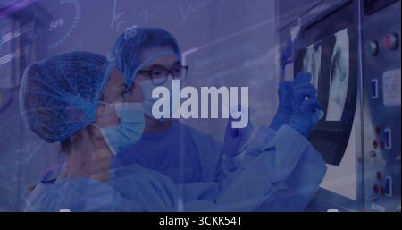 Revisione dei radiologi in scrub esame delle scansioni radiografiche del torace sul pannello nella sala di imaging, con console Foto Stock