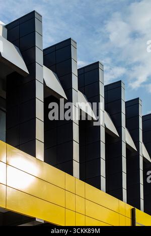 Colonne metalliche grigie e bordo giallo, dettagli minimalisti di un edificio contro il cielo blu Foto Stock