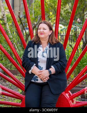 Ritratto di Kirsty McNeill (deputato del lavoro scozzese) con ruota industriale, National Mining Museum, Newtongrange, Midlothian, Scozia, REGNO UNITO Foto Stock