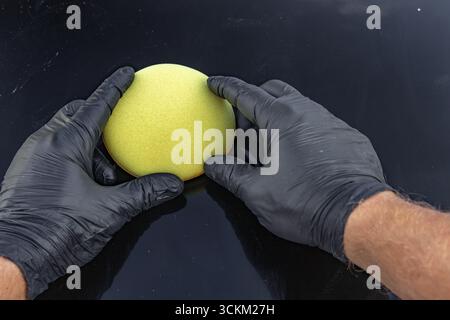 Un morbido tampone in spugna per lavare un'auto in mano a un uomo, con dettagli per lavare l'auto Foto Stock