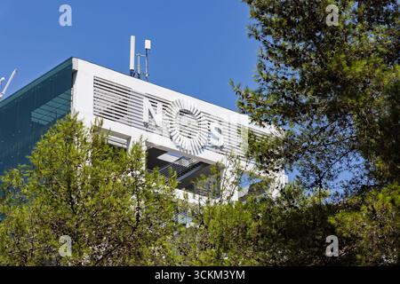 Una foto ravvicinata della facciata bianca simile a una griglia di un edificio moderno con il logo NOS, adagiata su un cielo blu brillante. Lisbona, Portogallo. Agosto 2025. Foto Stock
