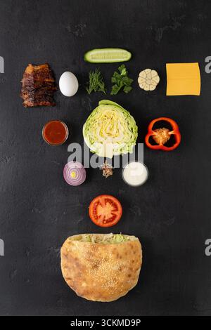 Vista dall'alto del panino pita con ingredienti freschi su sfondo nero, piatti piatti piatti Foto Stock