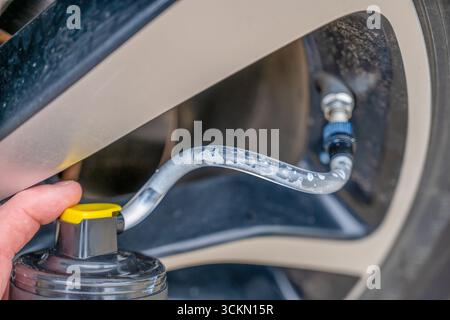 Attenzione selettiva all'additivo chimico spruzzato da una lattina in uno pneumatico per riparare uno sgonfio Foto Stock