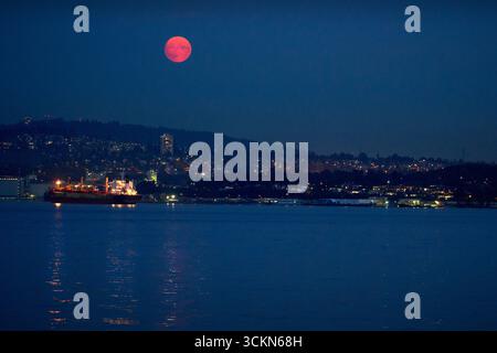Burrard Inlet Night Vancouver Cityscape Moon. La luna che si innalza sullo skyline di Vancouver su Burrard Inlet. Columbia Britannica, Canada. Foto Stock