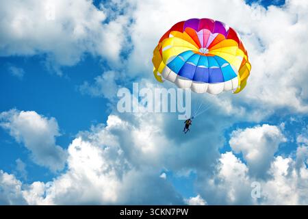 Parapendio con paracadute sullo sfondo di cielo nuvoloso blu. Foto Stock