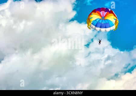 Parapendio con paracadute sullo sfondo di cielo nuvoloso blu. Foto Stock