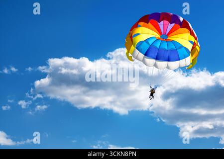 Parapendio con paracadute sullo sfondo di cielo nuvoloso blu. Foto Stock