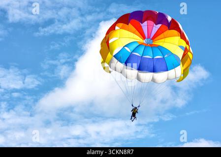 Parapendio con paracadute sullo sfondo di cielo nuvoloso blu. Foto Stock