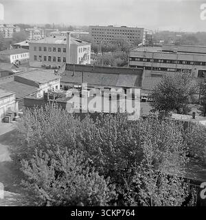 Una vista non cerimoniale dei cortili interni e degli edifici di servizio dietro la piazza centrale della Rivoluzione d'ottobre a Sloviansk, 1970. Queste foto panoramiche mostrano il "backstage" nascosto della città con i suoi vecchi edifici, le officine e i garage, in contrasto con i grattacieli sovietici sullo sfondo. Le cornici illustrano la vera vita quotidiana di una città sovietica e fungono da simbolo del complesso ma pacifico tessuto urbano del Donbas prima che iniziassero i tragici eventi Foto Stock