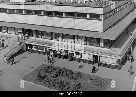 Vista panoramica del grande magazzino Yubileyniy (Jubilee) a Sloviansk, 1976. L'edificio, in stile modernista sovietico e situato in Piazza della Rivoluzione d'ottobre (ora Piazza Soborna), è mostrato come un centro del commercio urbano e della vita sociale. Gli scatti riflettono la vita quotidiana e l'architettura dell'era della stagnazione, simboleggiando la vita pacifica e ben tenuta a Donbas, dove il negozio centrale era un punto di attrazione per migliaia di cittadini Foto Stock
