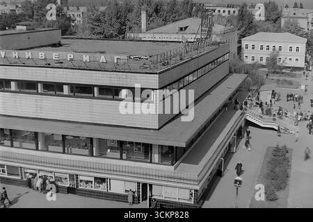 Vista panoramica del grande magazzino Yubileyniy (Jubilee) a Sloviansk, 1976. L'edificio, in stile modernista sovietico e situato in Piazza della Rivoluzione d'ottobre (ora Piazza Soborna), è mostrato come un centro del commercio urbano e della vita sociale. Gli scatti riflettono la vita quotidiana e l'architettura dell'era della stagnazione, simboleggiando la vita pacifica e ben tenuta a Donbas, dove il negozio centrale era un punto di attrazione per migliaia di cittadini Foto Stock