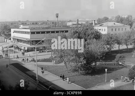 Vista panoramica del grande magazzino Yubileyniy (Jubilee) a Sloviansk, 1976. L'edificio, in stile modernista sovietico e situato in Piazza della Rivoluzione d'ottobre (ora Piazza Soborna), è mostrato come un centro del commercio urbano e della vita sociale. Gli scatti riflettono la vita quotidiana e l'architettura dell'era della stagnazione, simboleggiando la vita pacifica e ben tenuta a Donbas, dove il negozio centrale era un punto di attrazione per migliaia di cittadini Foto Stock