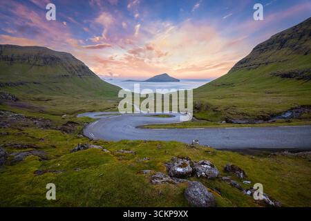 Vista su una strada tortuosa che porta all'isola di Koltur sullo sfondo. Streymoy, distretto di Torshavnar, Isole Faroe, Danimarca, Scandinavia. Foto Stock