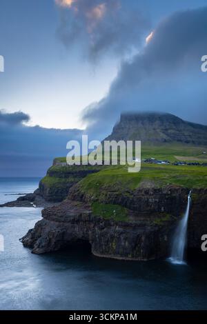 Vista della cascata Mulafossur con il piccolo villaggio di Gasadalur. Isola di Vagar, Isole Faroe, Danimarca, Europa. Foto Stock