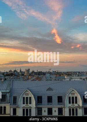 Paesaggio urbano al crepuscolo, caratterizzato da tetti dal design unico, illuminati dal caldo bagliore del tramonto, con nuvole colorate che esaltano l'atmosfera tranquilla Foto Stock