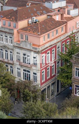 Colorati edifici storici di Porto con tradizionali tetti in argilla e facciate neoclassiche. Edifici a più piani in portoghese, rosso rosa arancione Foto Stock