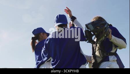 Giocatrici di baseball di alto livello che indossano maglie e cappellini blu sul campo soleggiato, con equipaggiamento da ricevitore Foto Stock