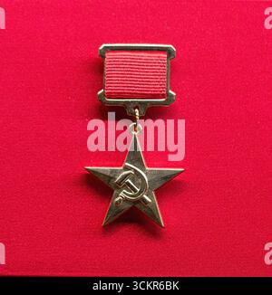 Medaglia dell'eroe d'oro dell'unione sovietica con nastro rosso visualizzato su sfondo rosso Foto Stock