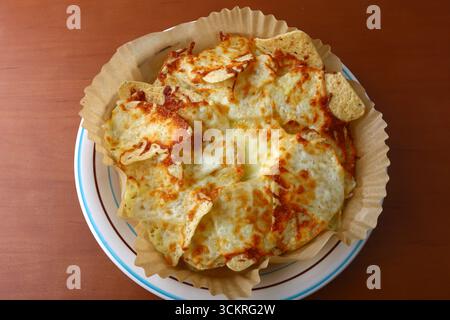 Piatto di Nachos con formaggio fuso e condimenti Foto Stock