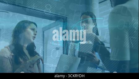 Collaborazioni con donne d'affari che gestiscono il laptop in ufficio, con documenti tablet e sovrapposizione di dati Foto Stock