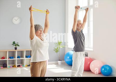 Allegra coppia senior che fa esercizi di stretching e si allena insieme durante la riabilitazione del braccio in clinica. Foto Stock