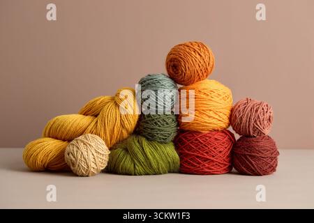 Palline colorate di filato in tonalità pastello e calde impilate su sfondo neutro Foto Stock