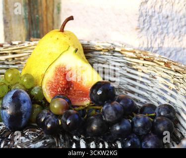 Fig, prugna, uva, pera in un cestino bianco Foto Stock