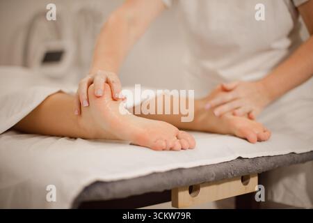 Massaggiatrice professionale che fa massaggio plantare sul lettino massaggiante nel salone spa Foto Stock