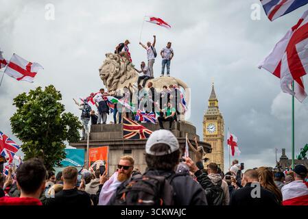 Manifestanti su uno dei leoni sul ponte di Westminster, la marcia "Unite il Regno" guidata da Tommy Robinson riunisce centinaia di migliaia di manifestanti in centesimo Foto Stock