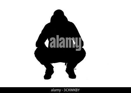 vista frontale della silhouette di un uomo accovacciato vestito con felpa con cappuccio su sfondo bianco Foto Stock