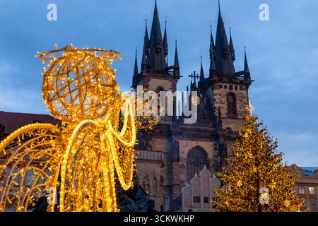 Statua dell'angelo luminoso e albero di Natale che decora la Piazza della città Vecchia a Praga con la Chiesa di nostra Signora prima di Tyn al crepuscolo Foto Stock