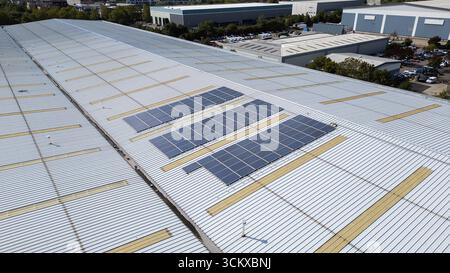 Vista aerea con droni dei pannelli solari installati sul tetto di un magazzino in un parco industriale, che mostra energia rinnovabile e generazione di energia sostenibile. Foto Stock