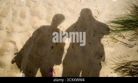 Ombra di due persone sulla sabbia alla luce del sole Foto Stock