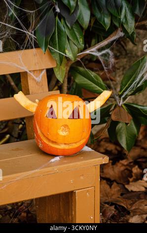 Una Jack o Lanterna fatta a mano seduta su una panchina di legno all'aperto, Autumn Holiday Foto Stock