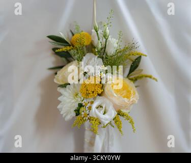 Elegante composizione floreale con rose gialle e bianche, completata da un delicato verde e piccoli fiori bianchi. Perfetto per matrimoni Foto Stock