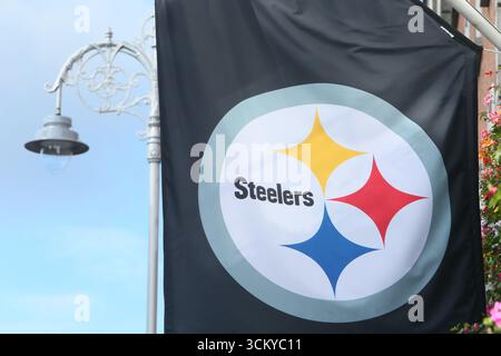 Dublino, Irlanda - 12 settembre 2025 - Una grande bandiera per i Pittsburgh Steelers visibile accanto a un iconico semaforo di Dublino nel centro di Dublino durante la costruzione della prima partita NFL in Irlanda Foto Stock