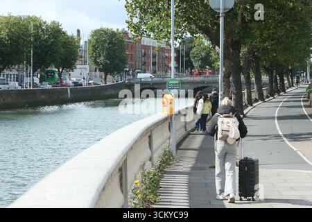 Dublino, Irlanda - 12 settembre 2025 - Una vista di Inns Quay nel centro di Dublino mentre una donna viaggia con una valigia da viaggio in un pomeriggio di sole nella capitale irlandese Foto Stock