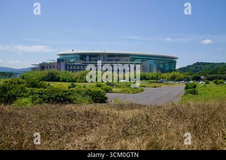 Lo Stadio Jeju World Cup si erge con il suo moderno tetto ovale e la facciata in vetro, circondato dal verde e da un'area parcheggio, un luogo di riferimento costruito per questo Foto Stock