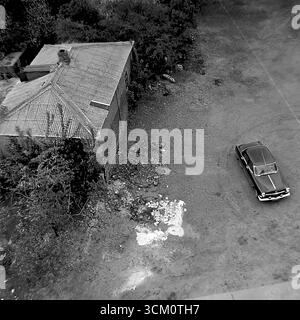 Dietro le quinte di un importante progetto di ricostruzione: Cortili interni caotici e un settore residenziale privato dietro la piazza centrale di Sloviansk, 1975-1976. Il colpo cattura vecchie case in attesa di demolizione, capannoni, detriti. Questa immagine riflette il processo di sdoganamento del sito per il rinnovamento urbano, simboleggiando un'epoca passata sacrificata per la nuova e monumentale visione di una città sovietica, e documenta la complessa ma pacifica vita nel Donbas durante quel periodo Foto Stock